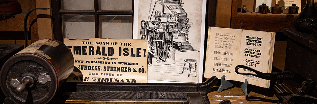 Artifact posters and newspaper advertising behind an antique printing press