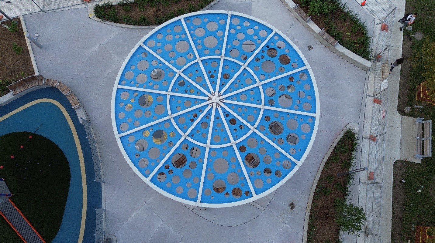 An image looking down at a round shaped shade structure with circular cut-outs.