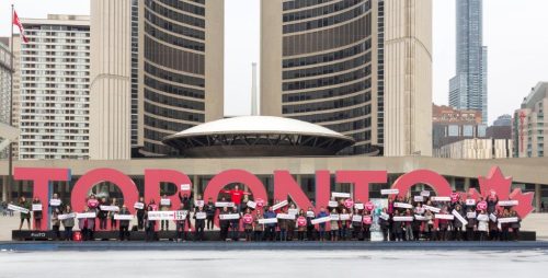 Toronto sign lit in read with people standing in front