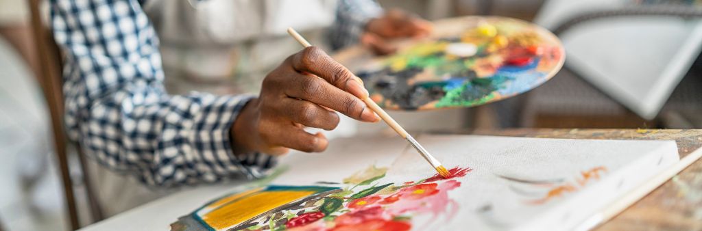 Close up of hand painting flowers on canvas