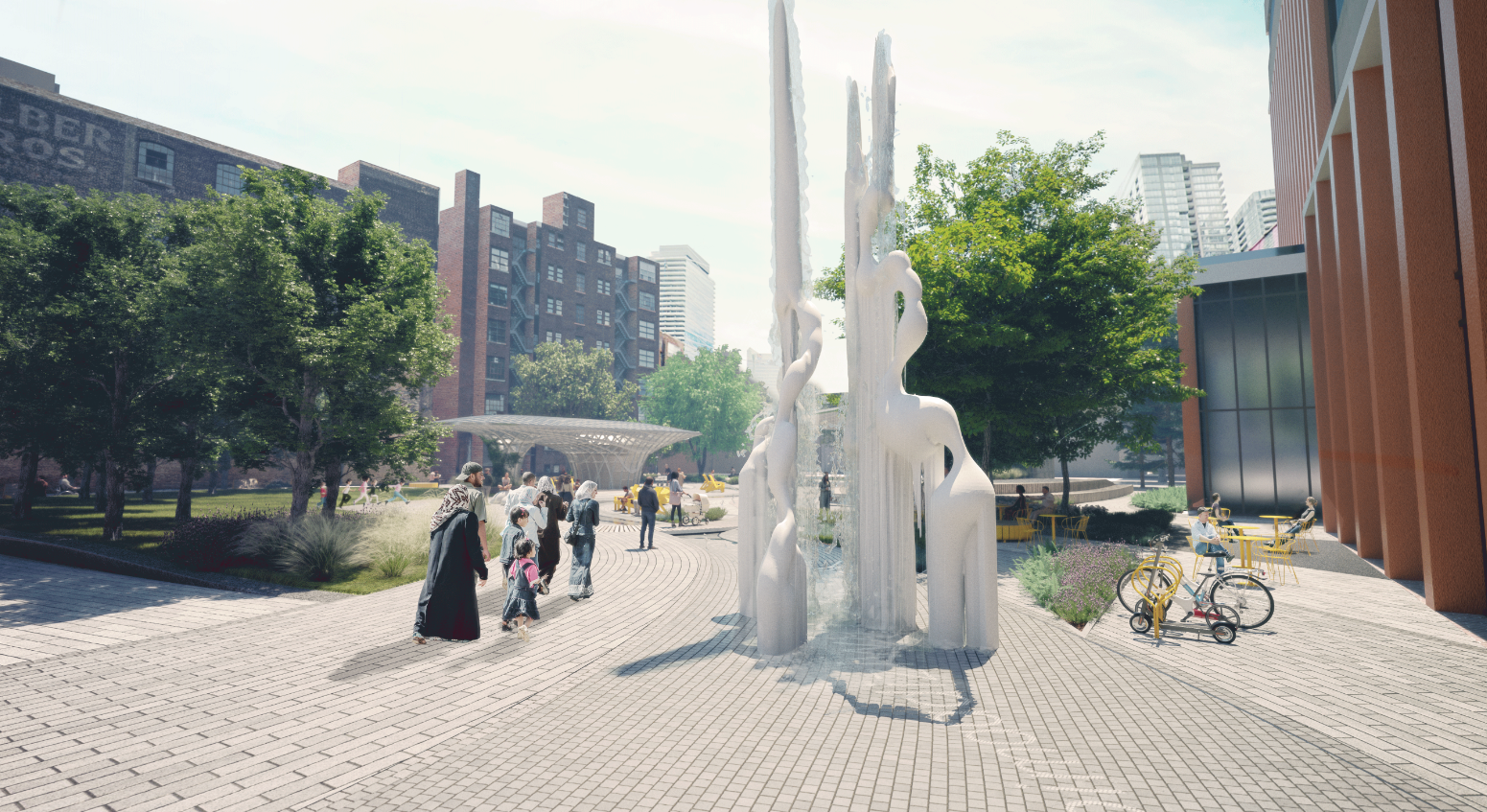 A tall flowing sculpture marks the southeast gateway of River Park. Visitors head toward the central space, admiring the sculpture. Others are seated in the vibrant, yellow patio furniture in between large trees with lush planting and the adjacent tall building.