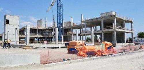 Construction site with concrete structure, a crane and two construction workers.