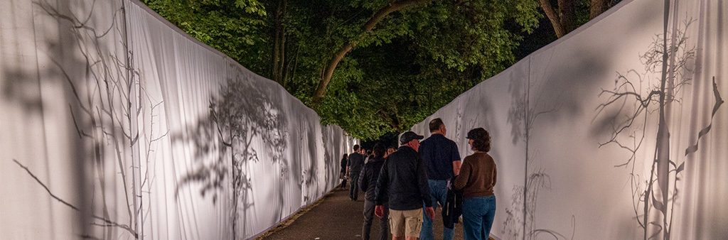 Crowd walks outdoor path between two fabric artworks
