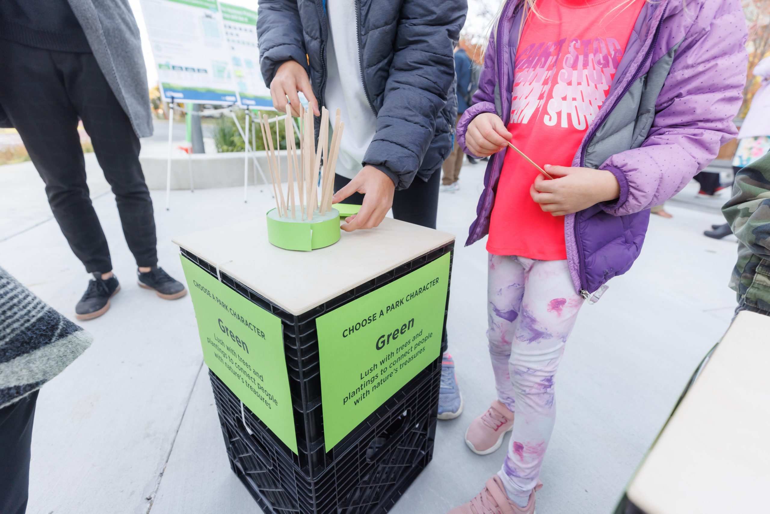 Young community members casting votes at an engagement station in Holmes Park. Each station represented a type of park character and associated activity, allowing the community to indicate their preference by sticking a popsicle in a block of foam.