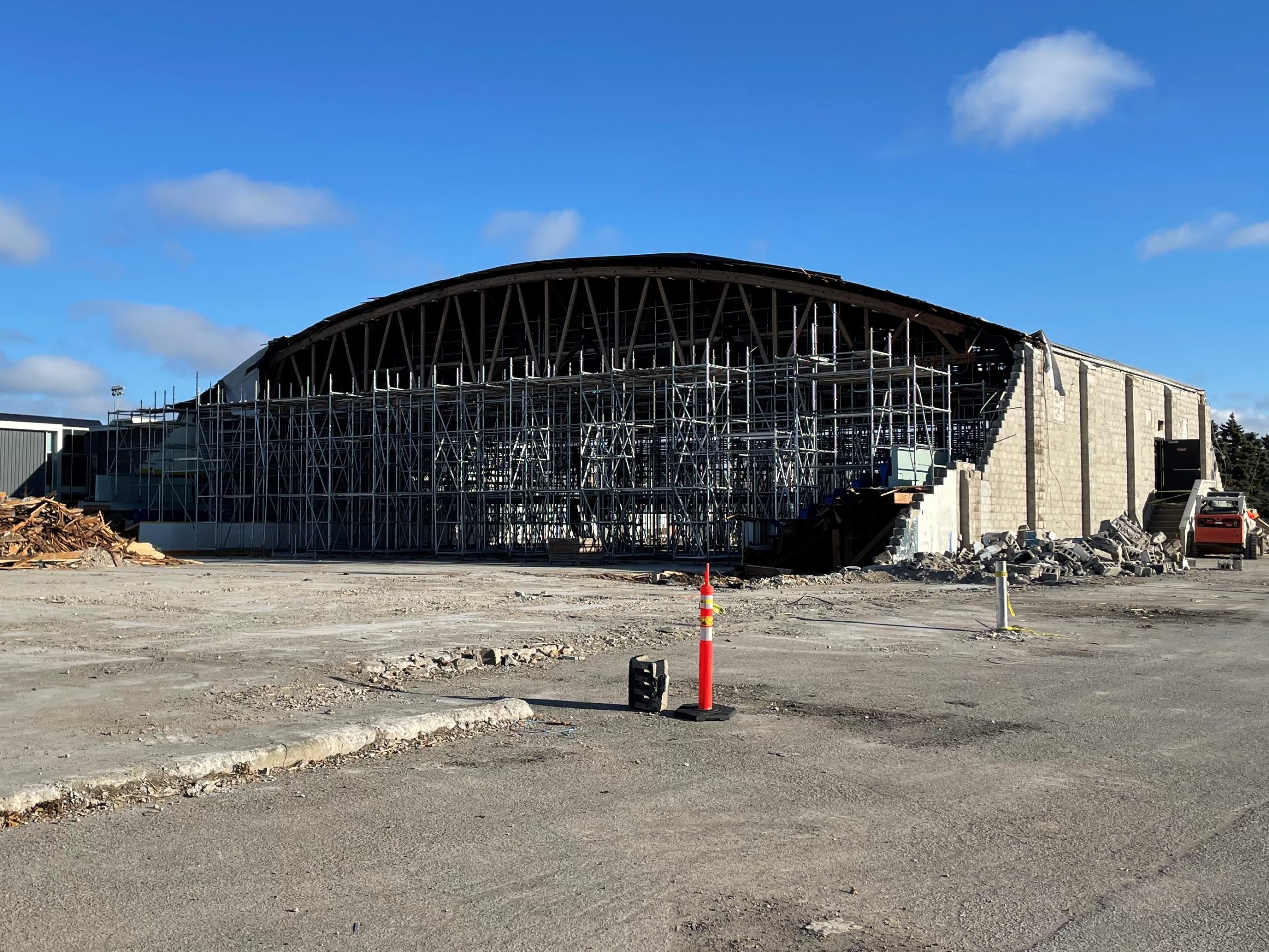 A photo of the building exterior during construction, which shows the intersecting steel beams along the demolished opening of the building from floor to ceiling. 