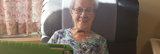 Senior woman sitting in a chair, using a tablet