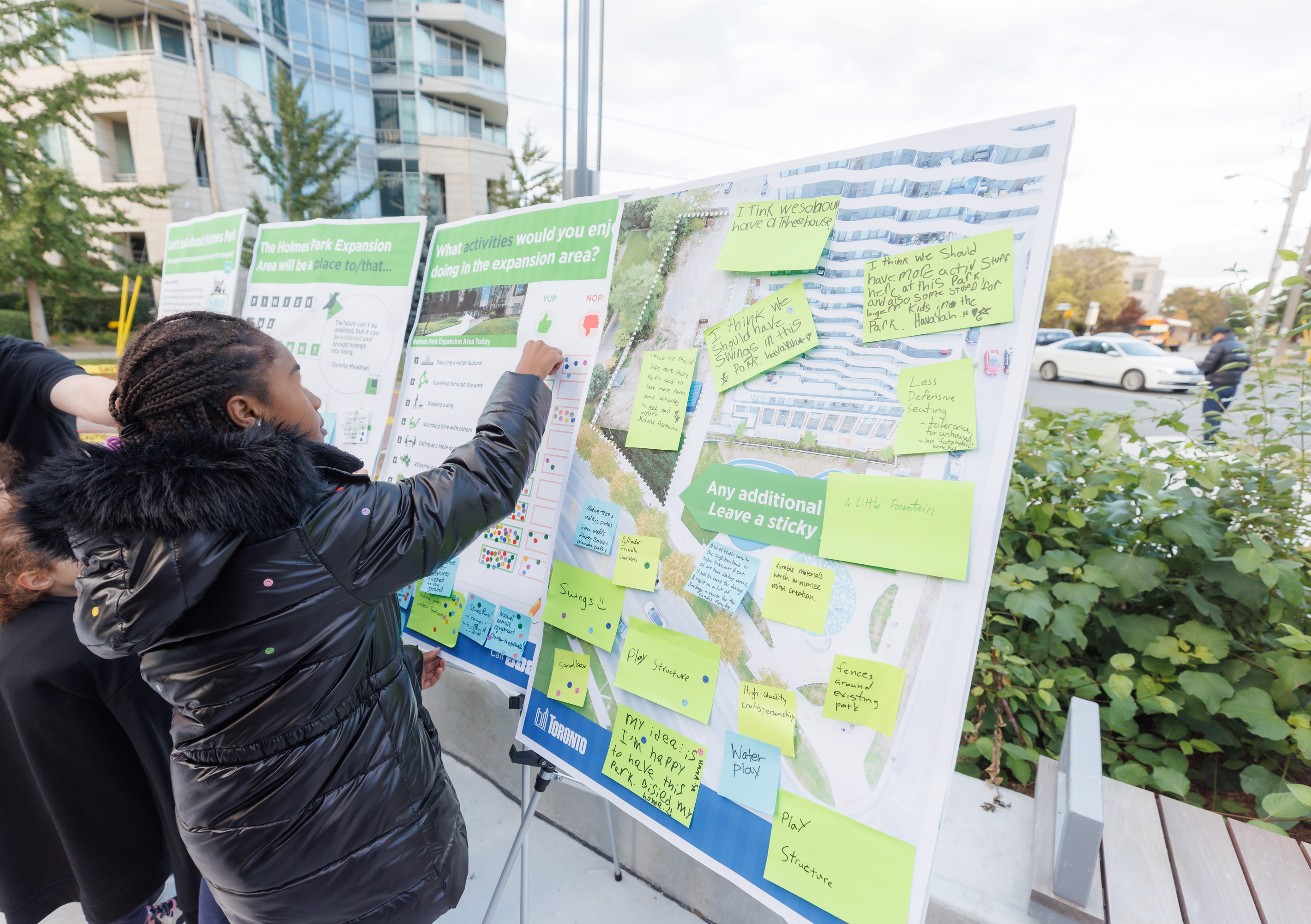 A member of the community posting a sticker on an engagement board to indicate their preference for the types of park activities they want to see in the expanded Holmes Park.