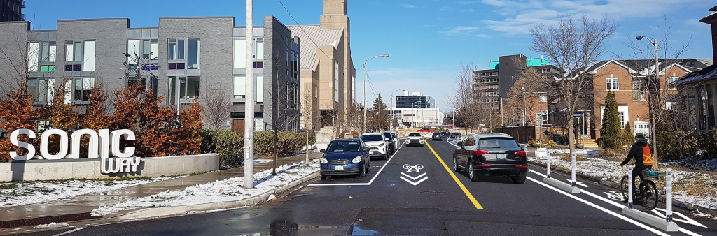 A rendering of proposed changes to Ferrand Drive, showing from left to right: a parking lane, southbound motor vehicle lane with sharrows, northbound motor vehicle lane, and a one-way northbound cycle track.