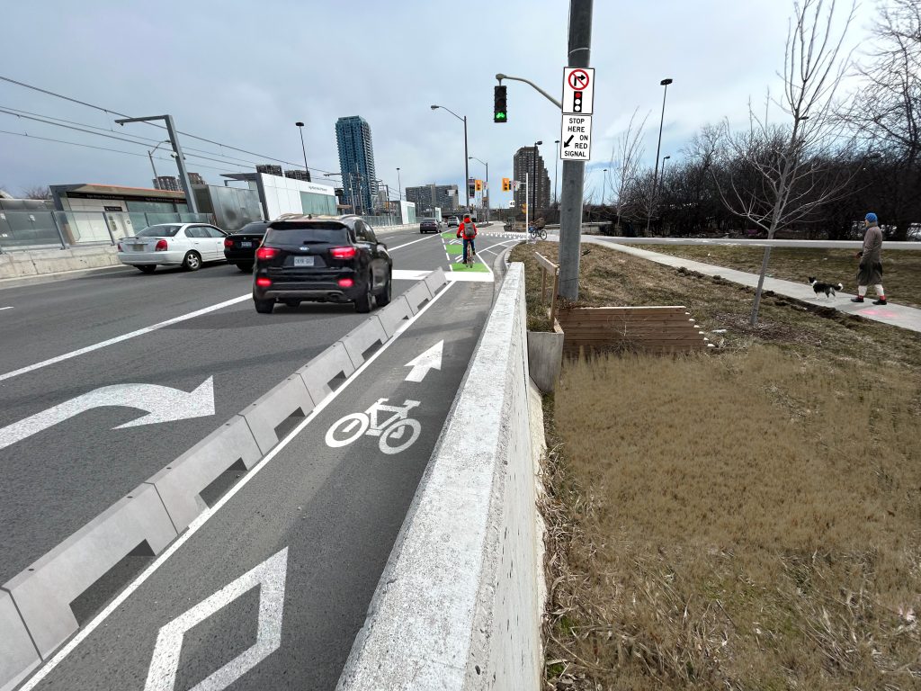 A rendering of proposed changes to Ferrand Drive, showing the one-way cycle track with low-wall barriers and a signalized crossing across the on-ramp.