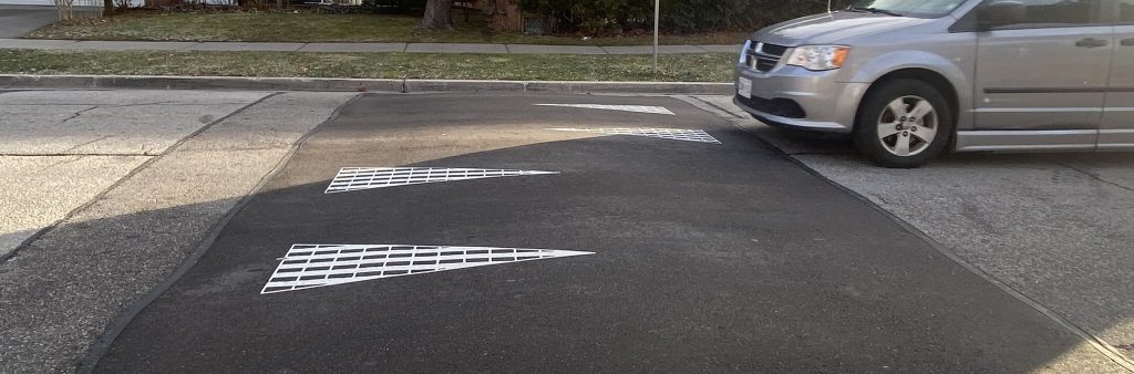 A vehicle approaches a raised speed hump on a residential street.