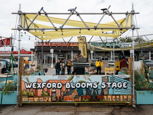 Outdoor stage with DJ. Banner reads Wexford Blooms Stage.
