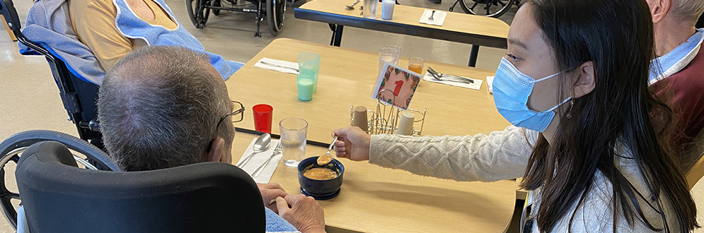 Volunteer helping a senior eat