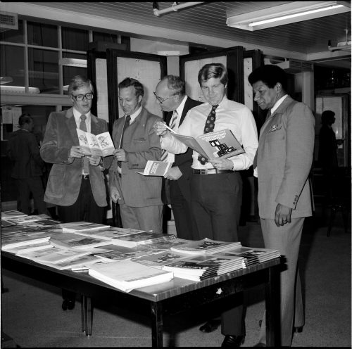 Group of men at table reading leaflets