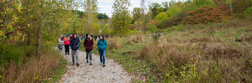 People walking on a forested trail in a City park.