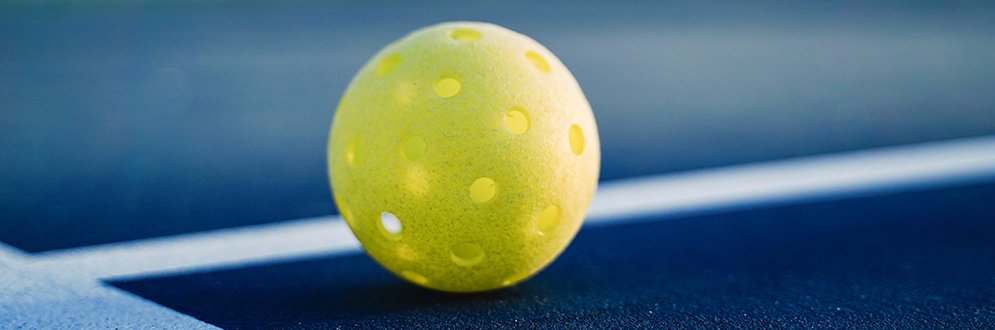 Close up image of a yellow wiffle ball.
