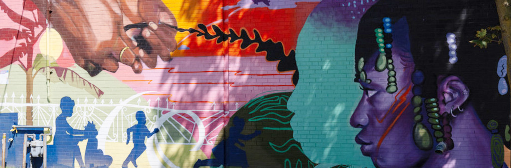 Vibrantly painted mural with two hands braiding hair on the left, and a figure with purple skin having their hair done on the far right.