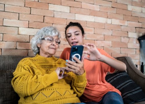 Young person helping an elderly person use their cell phone