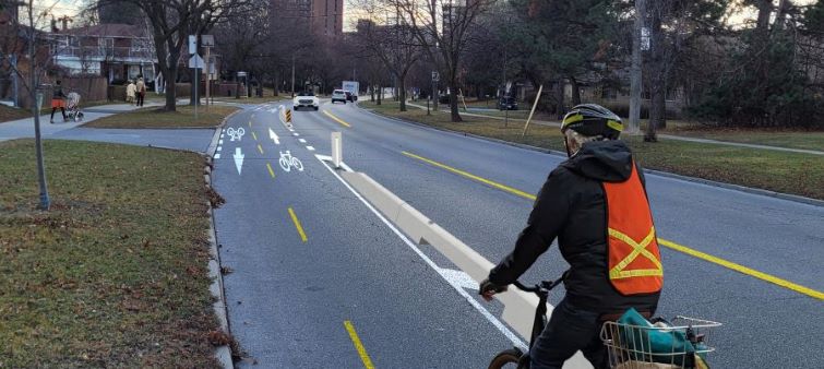 Image of a cyclist on a bi-directional cycle track separated by concrete curbs on the roadway.