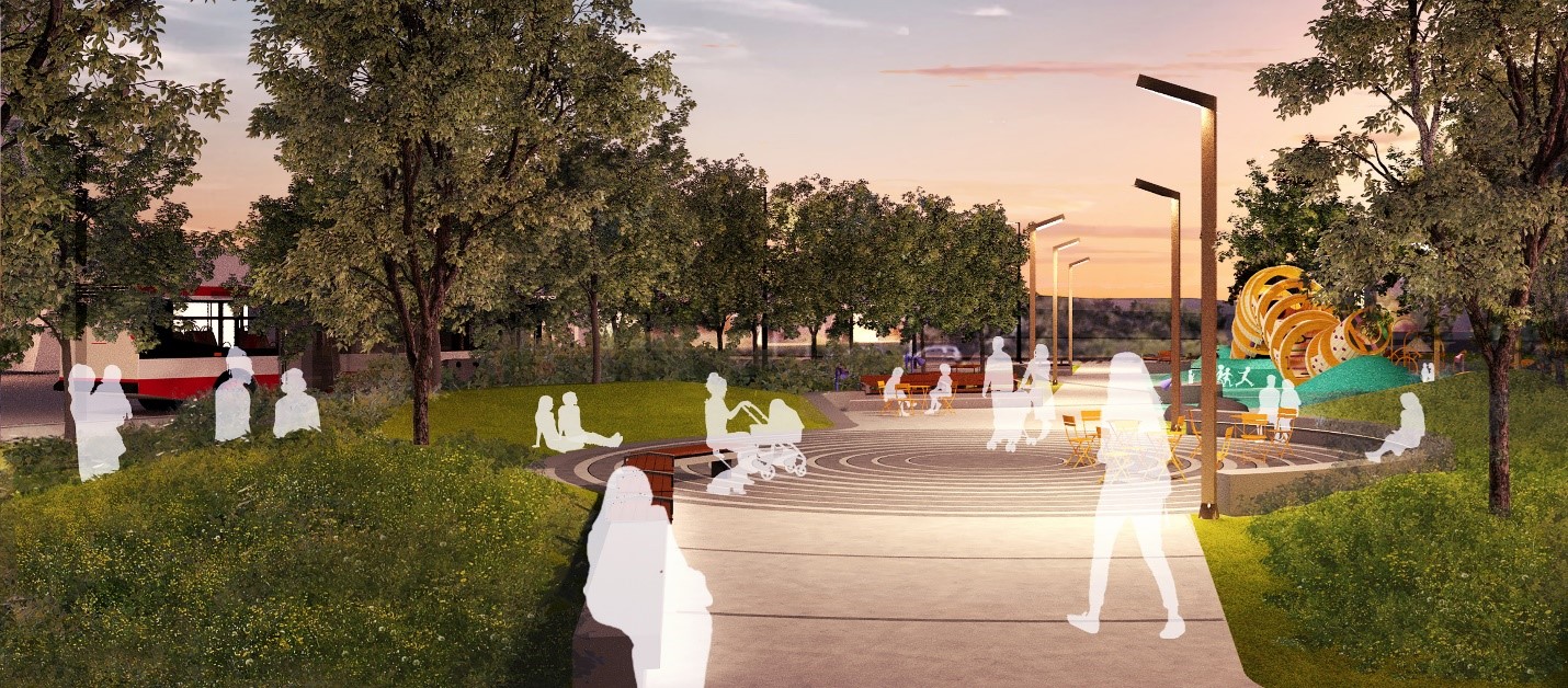 An evening view of the park from Borough Drive, following the main path toward the ‘Turntable’ plaza. A custom seat wall with integrated lighting borders the paths and the radial paving pattern in the plaza is illuminated by park lights. The Backbone Slide is also visible in the background.