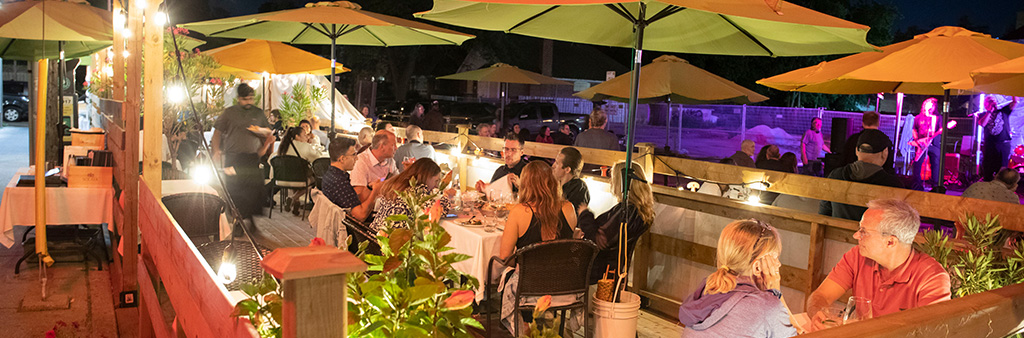 Patrons dining on an outdoor patio at night.