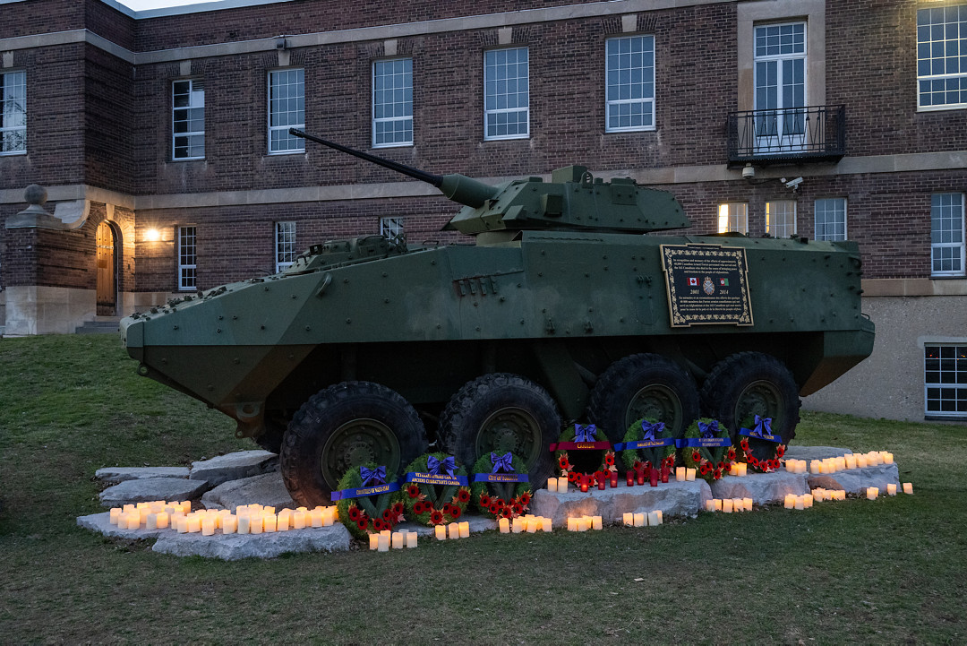 A light armoured vehicle from the Afghanistan Mission is shown in partial light surrounded by 158 lit candles and 7 wreaths