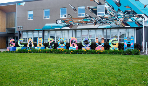 Colourful sculpture spelling out Scarborough standing on a lawn against a building with a glass windows and a mural