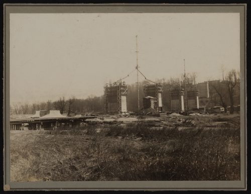 Image depicts monochrome photograph of construction of concrete piers of viaduct
