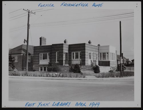 Image depicts monochrome photograph of single storey library building on corner of two streets