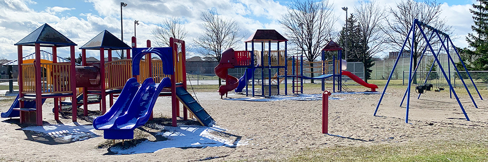Indian Line Park Playground showing several play structures, like a blue slide, talk tube and swing set in the foreground, and a senior structure with spiral slide in the background.