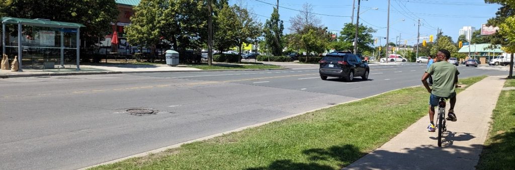 photograph of Trethewey Drive. A person bikes on the sidewalk.