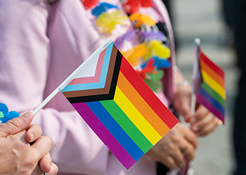 People wearing pink shirts holding rainbow pride flags.