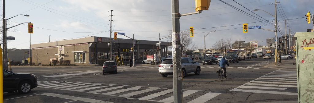 Photo showing the intersection of Victoria Park Avenue and Danforth Avenue, showing traffic on the roads and a cyclist