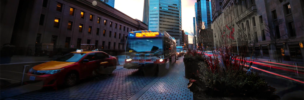 Bus and taxi driving on road with city buildings and CN tower in the background