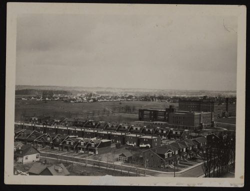 Image depicts monochrome aerial view of East York, with buildings in foreground and farmland in background
