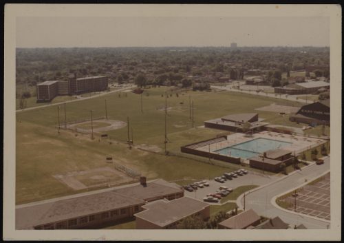 Image depicts colour aerial photograph of park, with swimming pool, baseball diamonds and sports field