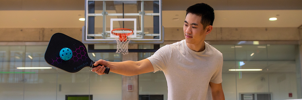 A person is playing pickleball at an indoor gym at York Recreation Centre