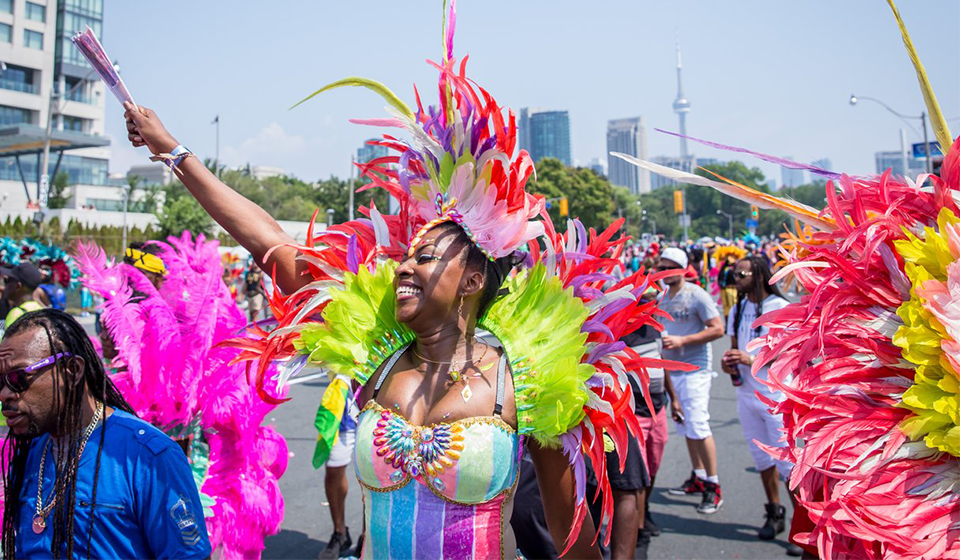 Smiling woman wearing Caribbean Carnival costume in crowd