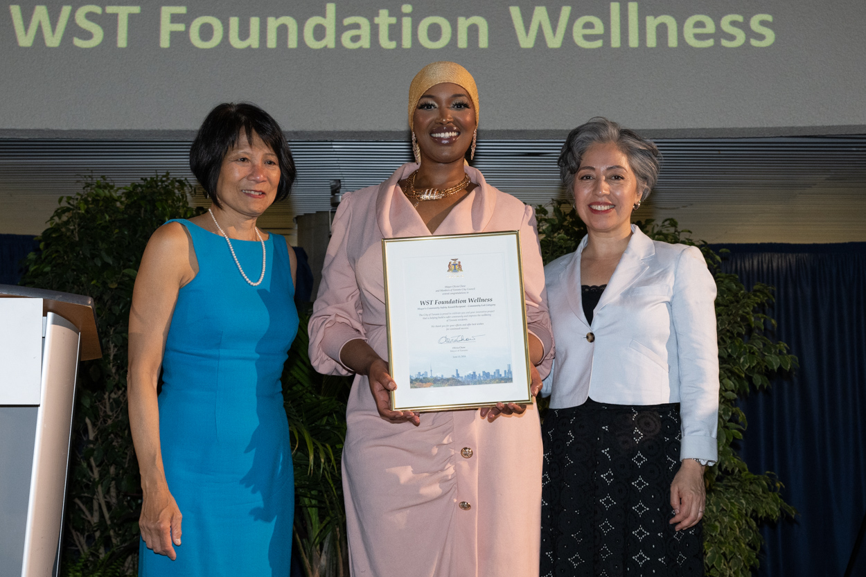 A women smiling for the camera with Mayor Olivia Chow and Councillor Alejandra Bravo holding up a framed award.
