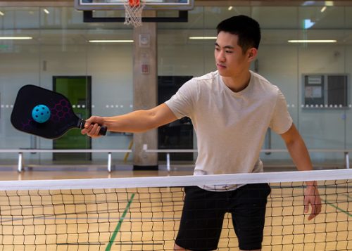 A man playing pickleball in an indoor court.
