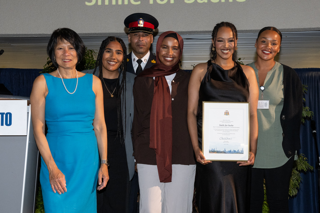 A group of people smiling for the camera with Mayor Olivia Chow holding up a framed award.