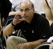 Stephen Bialowas crouching in black shirt talking to players around him. 