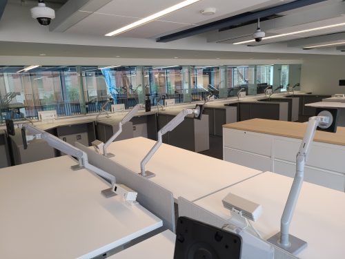 A brightly lit room with white desks, stands and cupboards.
