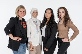 A group of 4 women standing in front of a white backdrop.