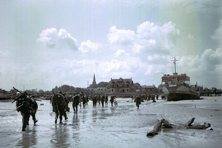 Troops walking on Juno Beach after landing on D-Day