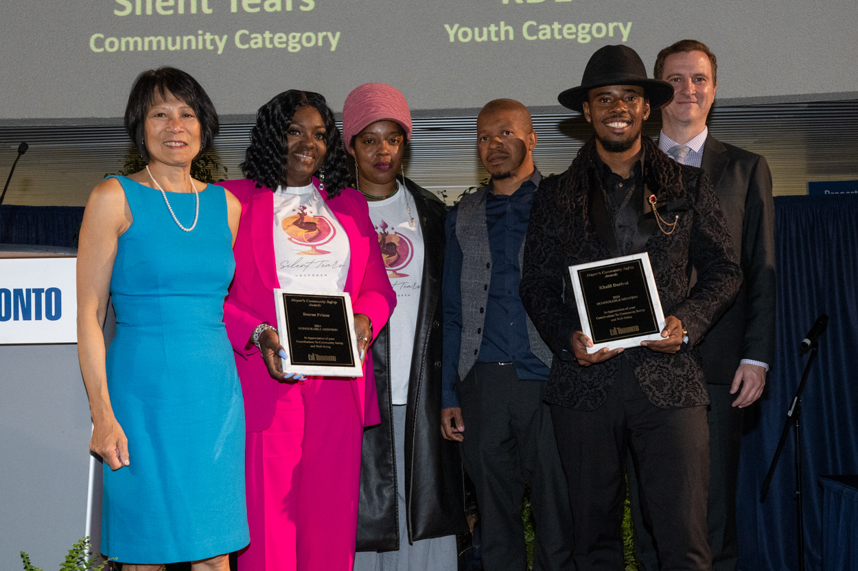 A group of people smiling for the camera with Mayor Olivia Chow holding up 2 framed awards.