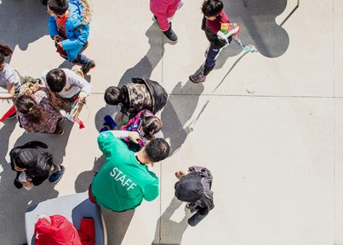 Aerial view of a City staff member assisting children outdoors.