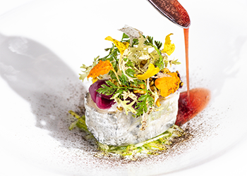 A dish with colourful greens and a sauce on a plate.