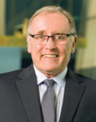 Portrait of Robert Singleton wearing gray suit and tie with white shirt.