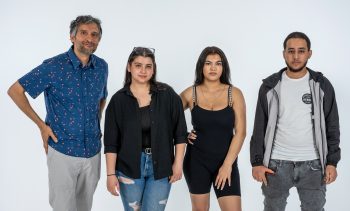 Four people posing for the camera standing in front of a white back drop.