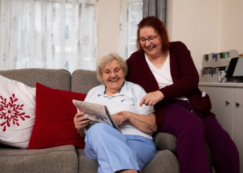 Two women reading together on a couch.